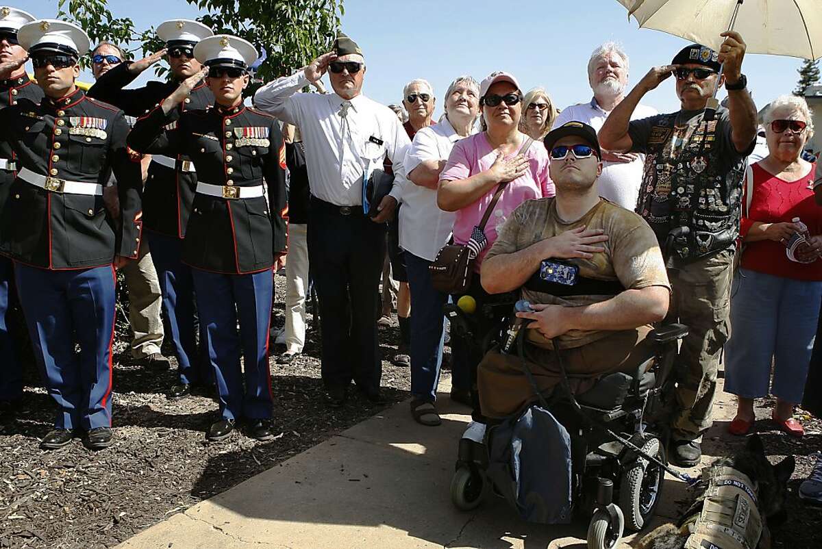 Marine Staff Sgt. Jason Ross (right) watches as the flag is raised at Granada High School in Livermore, California, before a baseball game honoring Livermore's wounded warriors on Wednesday, April 24, 2013. After graduating in 2001, he joined the U.S. Marine Corps later becoming an explosives technician. While in Afghanistan in 2011, he stepped on on an improvised explosive device while patrolling and lost his legs.
