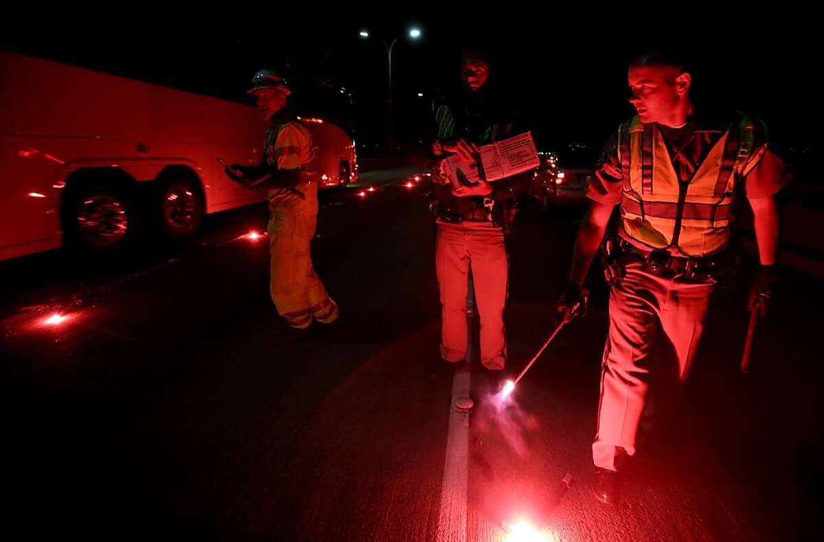 California Highway Patrolmen light flares as they investigate the scene of a limousine fire on the westbound side of the San Mateo-Hayward Bridge in Foster City, Calif., on Saturday, May 4, 2013. Five people died when they were trapped in the limo that caught fire as they were traveling, and four others and the driver were able to escape, according to the Oakland Tribune-Bay Area News Group. (AP Photo/Oakland Tribune-Bay Area News Group, Jane Tyska)