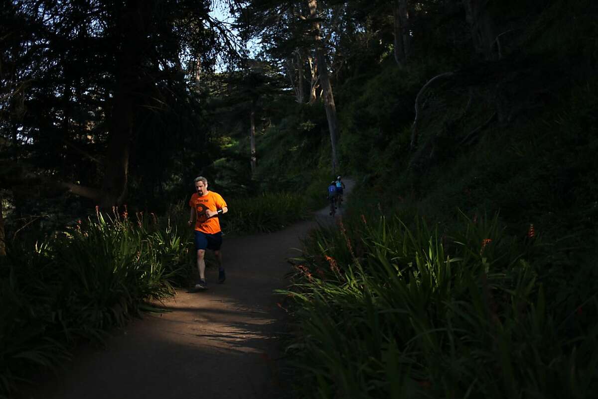 A runner passes through a shaft of light on a trail between Eagles Point and Dead Man's Point on May 2, 2013 in the Lincoln Heights area of San Francisco, Calif.