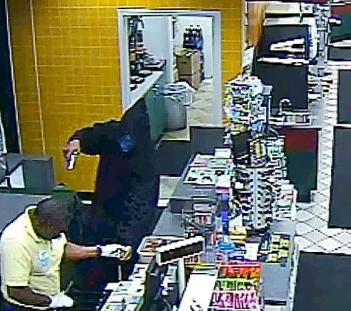 A still frame from the video which was released by the Greenwich police dept., shows the Nov. 21st, 2009 armed robbery and shooting at the Mobil on the Run gas station on East Putnam Avenue in Old Greenwich in which the hooded suspect with the gun wounded the store employee shown at left.