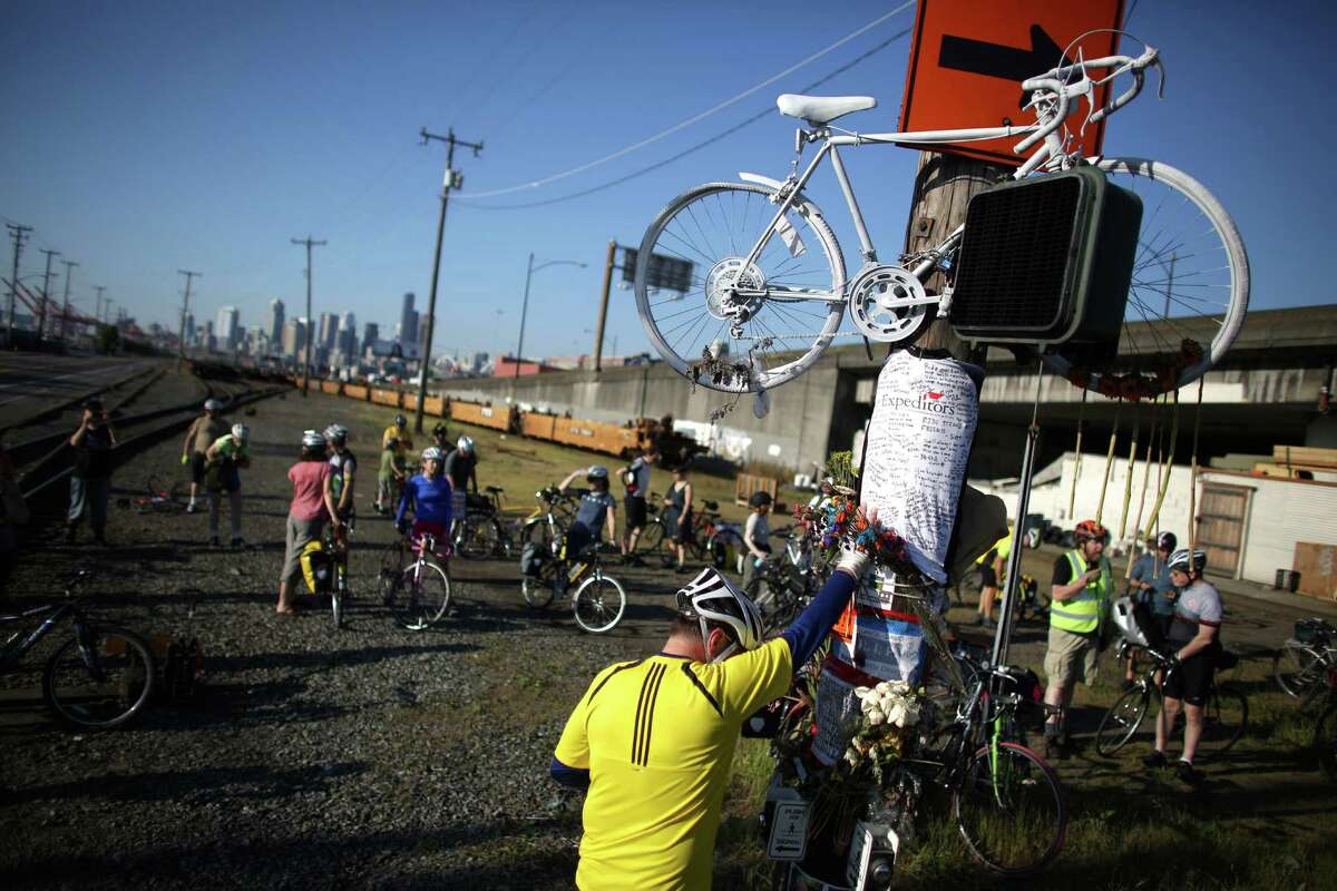 Mourner Lars Halstron places his hand on a memorial and bows his head during a bike ride in honor of Lance David, a cyclist killed in an accident with a semi-truck on East Marginal Way South near South Hanford Street in Seattle. David, 54, was riding his bike May 1st from Federal Way on the first day of Bike to Work Month when he died. Photographed on May 4, 2013.
