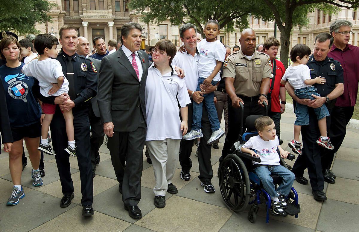 Gov. Rick Perry walks with Special Olympian Colby Bannister, 26, to light the torch on the south steps of the state Capitol to kick off the Law Enforcement Torch Run Final Leg for Special Olympics Texas, set for later this month in Arlington.