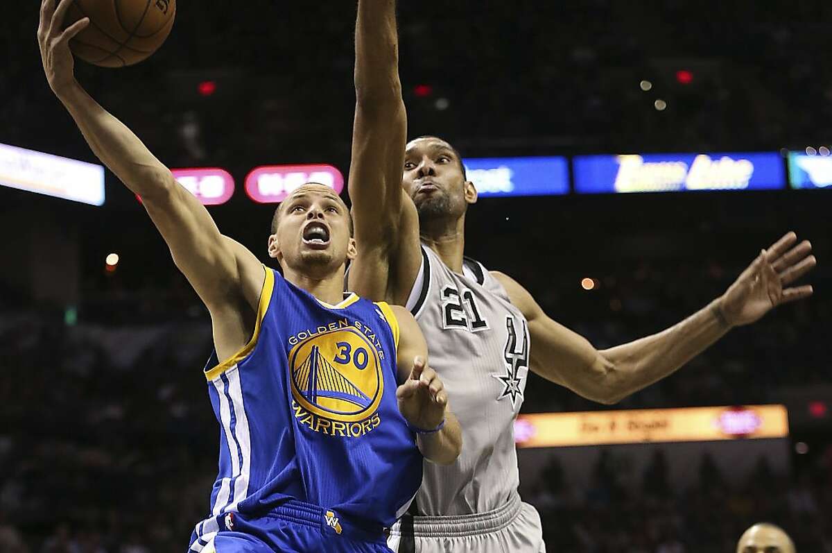 Golden State Warriors' Stephen Curry scores as San Antonio Spurs' Tim Duncan defends during the second half of Game 2 in the NBA Western Conference semifinals at the AT&T Center, Wednesday, May 8, 2013. The Warriors won, 100-91 to even the series at 1-1.