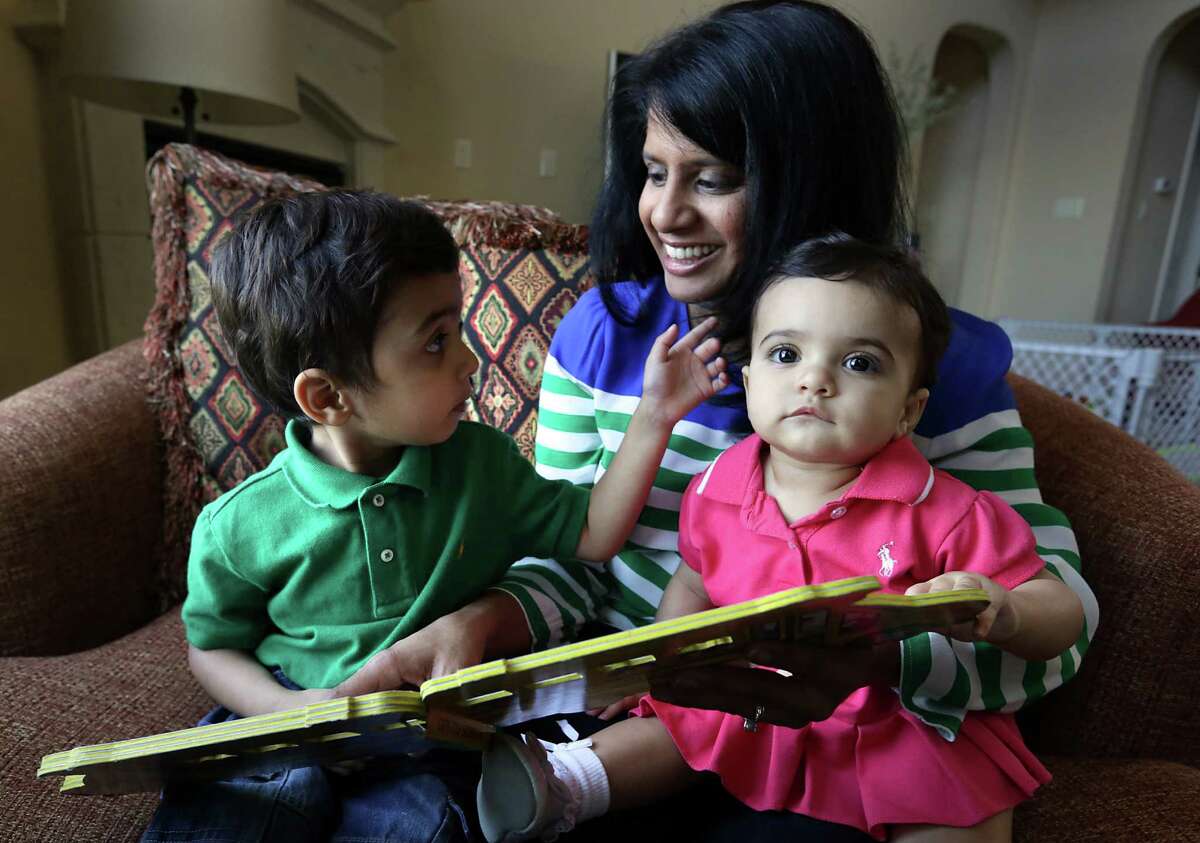 Nina Morgan reads to her 3 yr old son Luke as she holds her 11 mo old daughter Rachel in their home on Tuesday May 7, 2013.