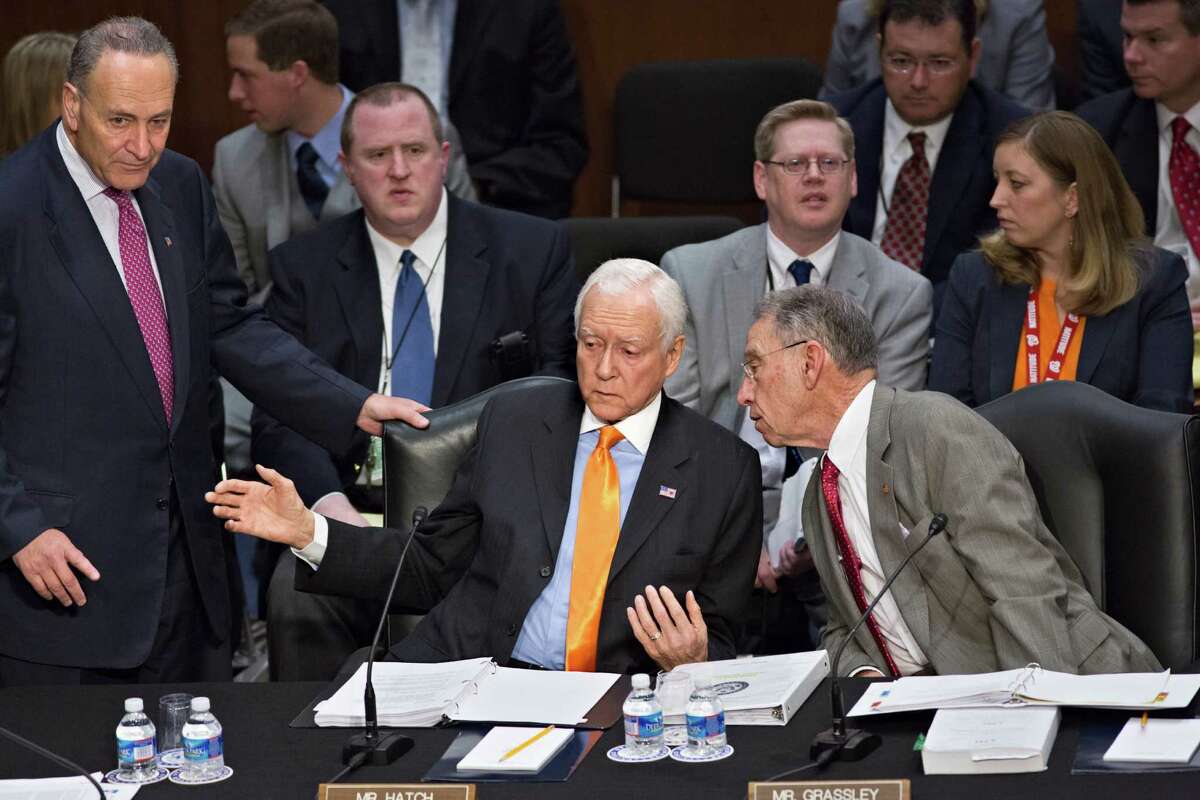 From left, Sen. Chuck Schumer, D-N.Y., standing, Sen. Orrin G. Hatch, R-Utah, and Sen. Chuck Grassley, R-Iowa, confer as the Senate Judiciary Committee meets on immigration reform on Capitol Hill in Washington, Thursday, May 9, 2013. A bill to enact dramatic changes to the nation's immigration system and put some 11 million immigrants here illegally on a path to citizenship is facing its first congressional test as the Senate Judiciary Committee begins considering proposed changes to the 844-page legislation. (AP Photo/J. Scott Applewhite)