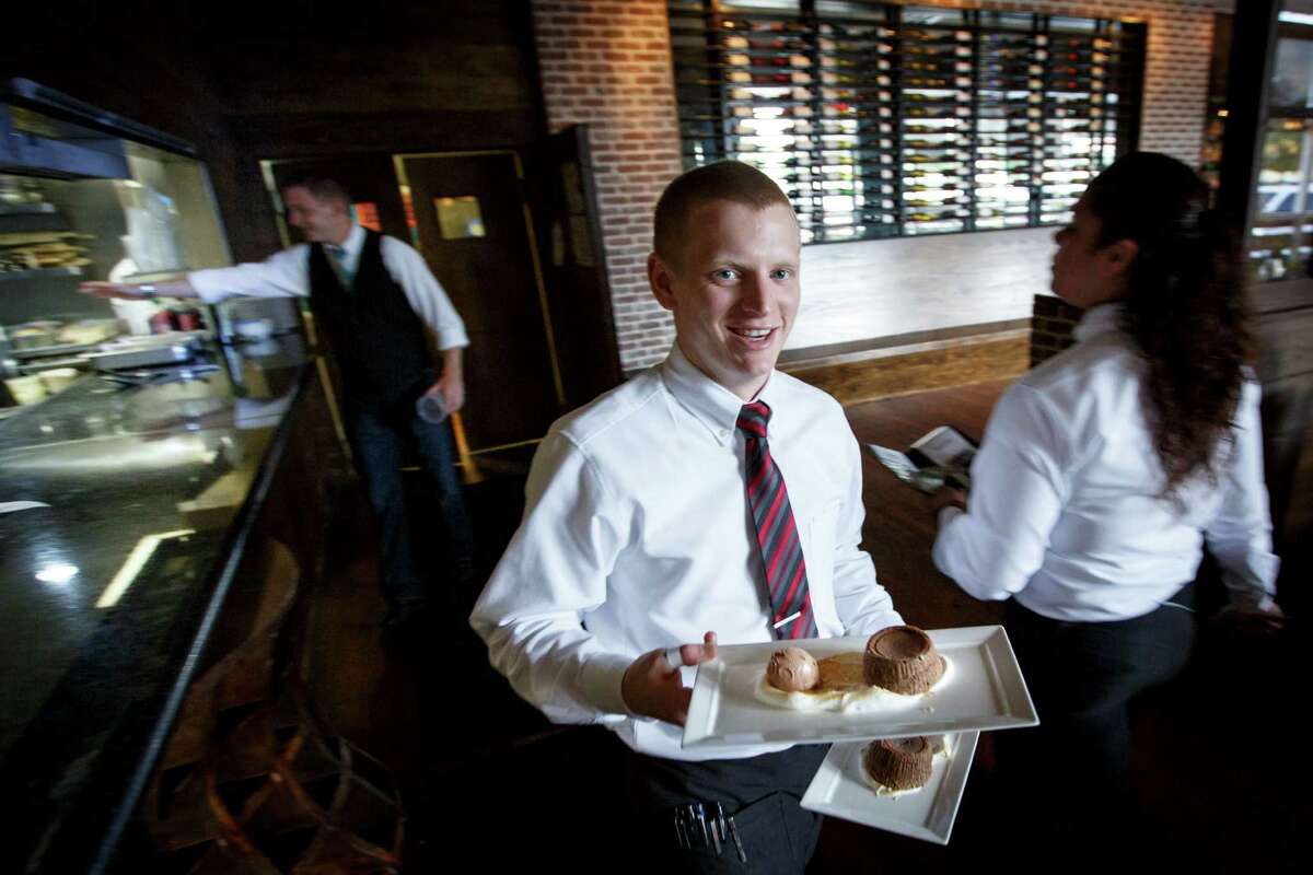 A waiter delivers dessert at the Federal American Grill, Tuesday, April 30, 2013, in Houston. ( Michael Paulsen / Houston Chronicle )