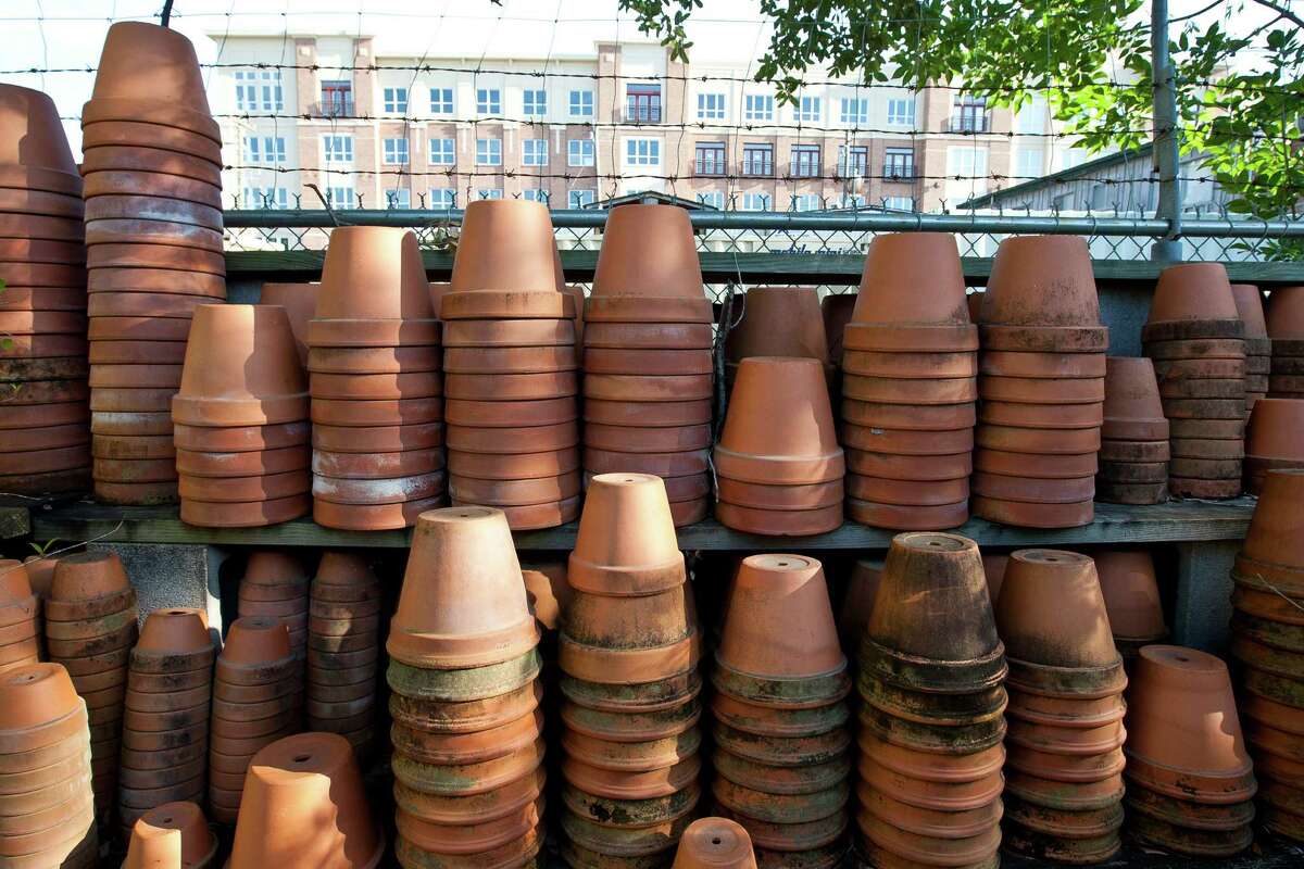 Pots that are stacked and ready for relocation stand on the south wall of the Garden Gate property, across the way from a new mix use building, Tuesday, May 7, 2013, near Rice Village in Houston. The Garden Gate, will come to a close after 20-years. ( Nick de la Torre / Chronicle )