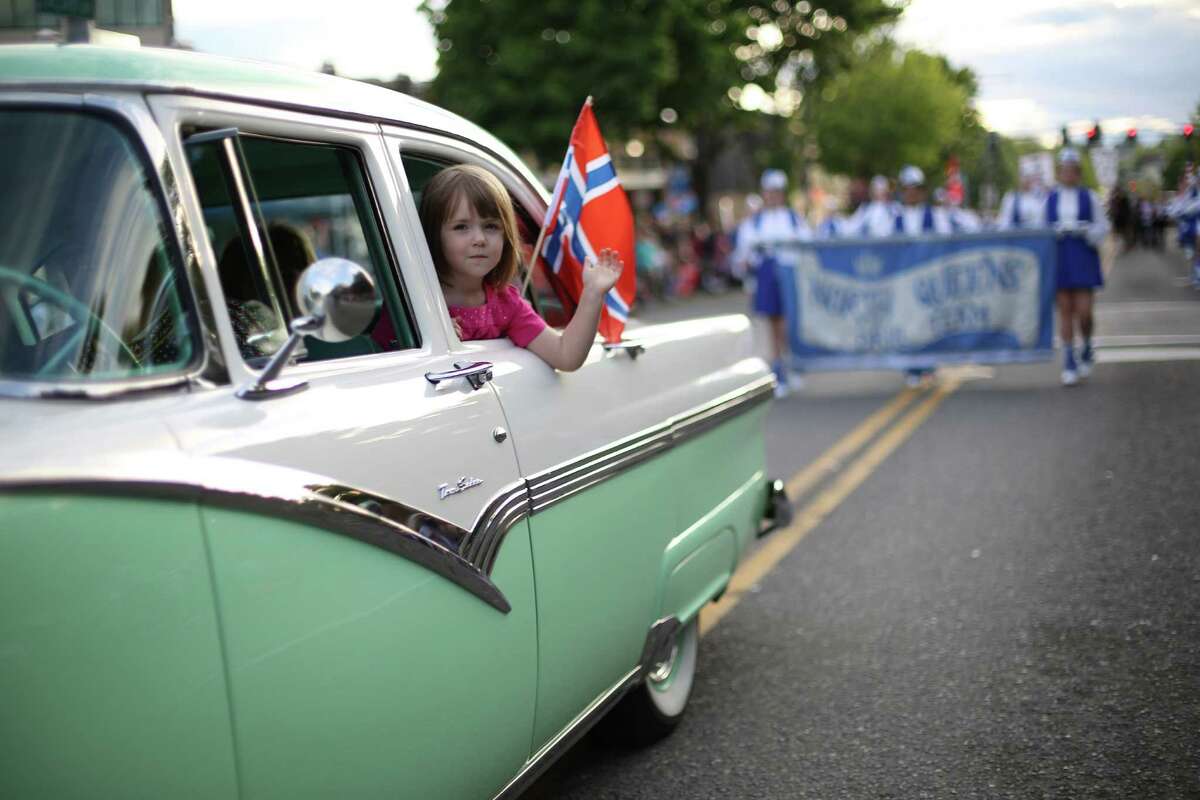 A parade participant waves from a classic car during Ballard's annual Syttende Mai parade. The parade celebrates Norwegian Constitution Day and is one of the largest celebrations outside of Oslo. Photographed on Friday, May 17, 2013.