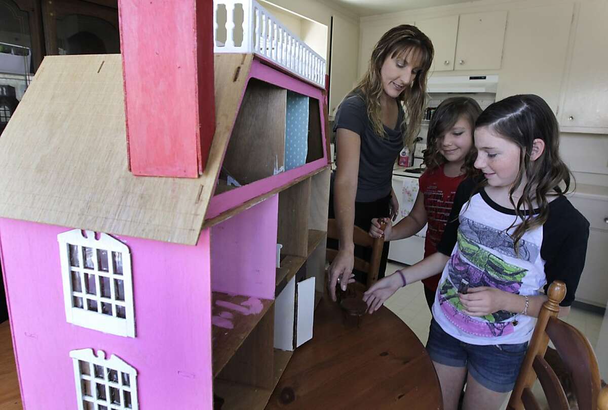 Anne Williams furnishes a dollhouse with her two daughters Cheyenne (center), 10, and Emily, 12, at their apartment in Newark, Calif. on Saturday, May 18, 2013.