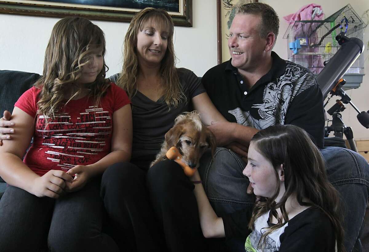 Anne Williams, boyfriend Mark Witter and her two daughters Cheyenne (left), 10, and Emily, 12, entertain their dog Buddy at Williams' apartment in Newark, Calif. on Saturday, May 18, 2013.
