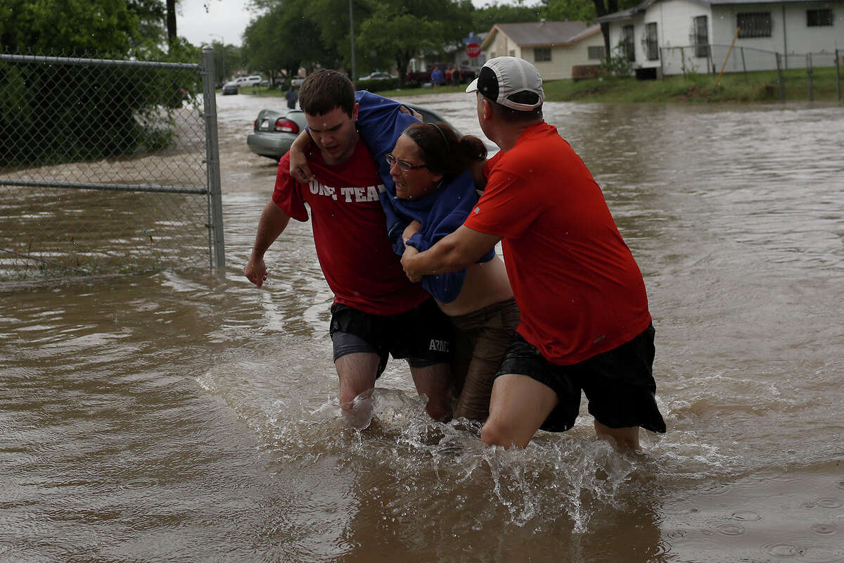 Marco Fairchild, left, and Gary Garza, right, help Sueann Schaller from her car after she drove it into floodwaters on Castleridge Dr. in the Westwood Village neighborhood off Military Dr. West on Saturday, May 25, 2013.