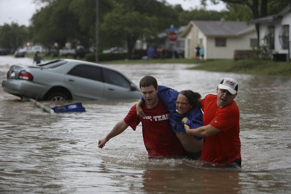 Marco Fairchild (left) and Gary Garza help Sueann Schaller from her car after she drove it into high water on Castleridge Drive.