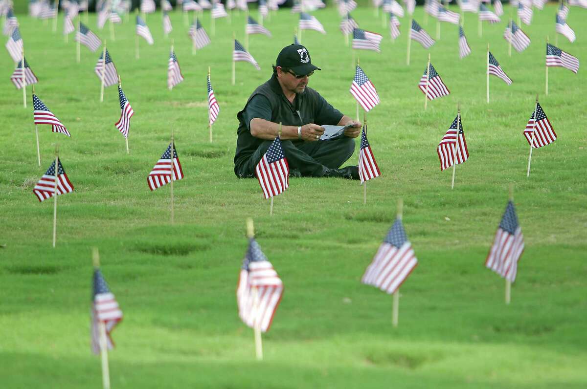 Rudy Montez looks over the program while sitting amongst grave sites prior to the Houston National Cemetery Memorial Day Service Monday, May 27, 2013, in Houston. Montez has family and friends buried in the cemetery.