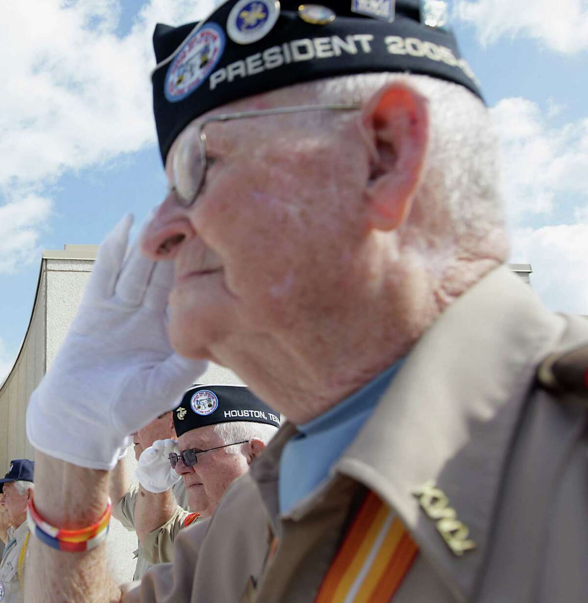 Veterans Carlos Ballard, left, and Anthony "Buddy" Blair salute on Monday for the presentation of the colors at the Houston National Cemetery.