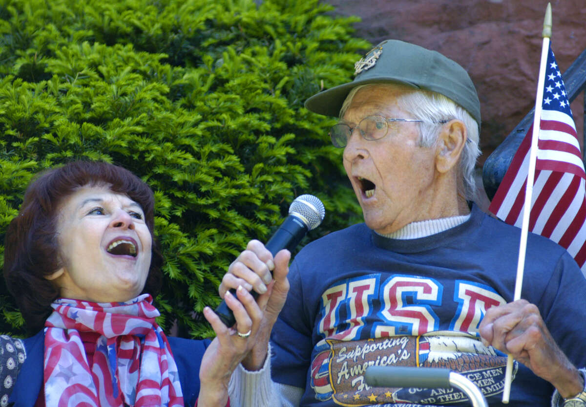 Francis Hill, 92, a U.S. Navy veteran of World War II, joins with New Milford tax collector Cathy Reynolds to sing "God Bless America" during the town's Memorial Day ceremony in New Milford. May 27, 2013