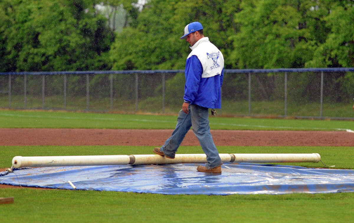 A grounsdkeeper lays out a tarp on the pitcher's mound during a rain delay during FCIAC Class LL state first round baseball action between Staples and West Haven in West Haven, Conn. on Tuesday May 28, 2013. A fwew minutes later the game was suspended.