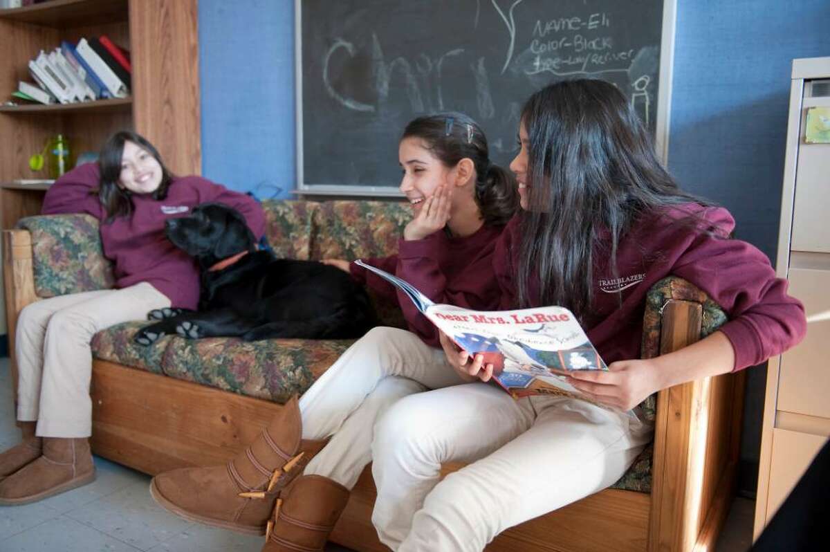Alileen Barillas, Cintia Enamorado and Joselyn DeLeon right, all 11 and 6 graders at Trailblazers Academy students read out loud in the company of Eli a black lab retriever puppy Tuesday Jan. 12, 2009. For about six weeks now, struggling readers at the charter middle school have practiced in front of the least judgmental of listeners, a dog