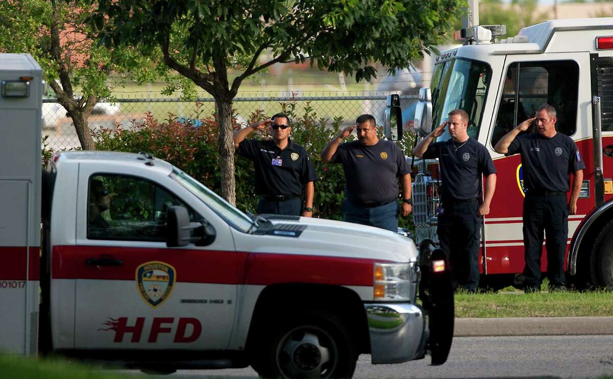 Firefighters salute as a procession carrying the bodies of the four fallen firefighters drives to the Forensic Center of Harris County on Friday.