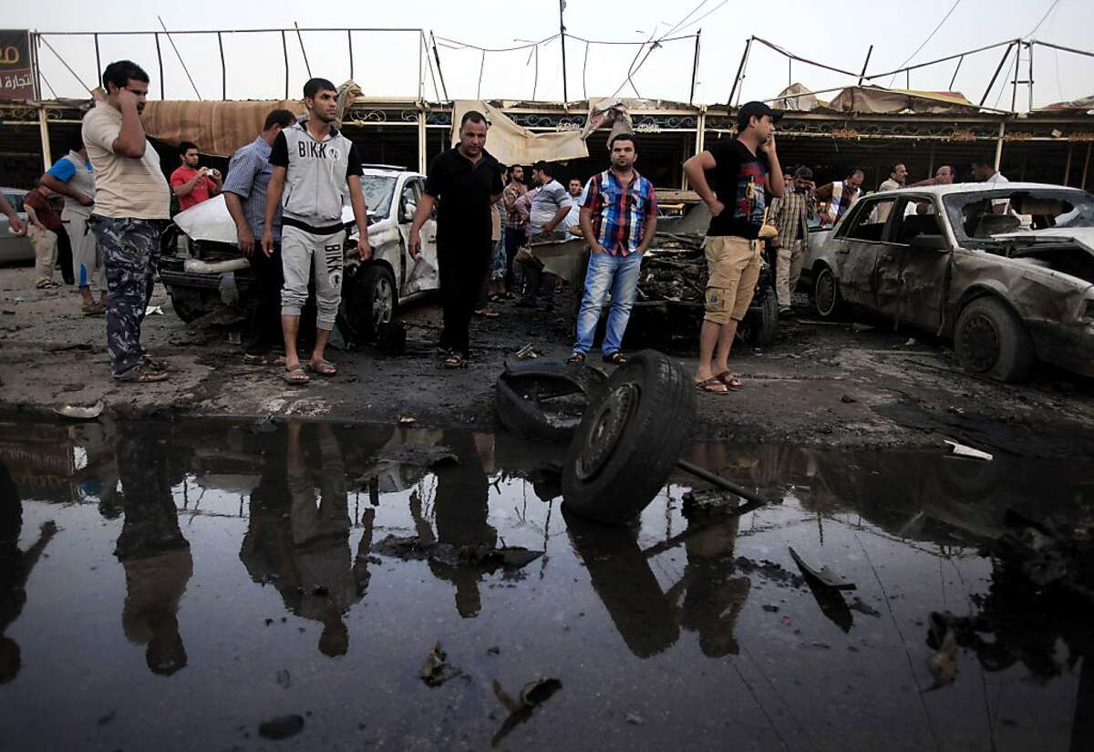 in this Monday, May 27, 2013 file photo, Iraqis gather at the scene of a car bomb attack at a used cars dealers parking lot in Habibiya neighborhood of eastern Baghdad, Iraq. More than a year after the U.S. military left Iraq, the country is reeling from its most sustained violence since 2008. Over the last two months more than 1,200 people have been killed, raising fears the country is sliding back into chaos. (AP Photo/Karim Kadim, File)