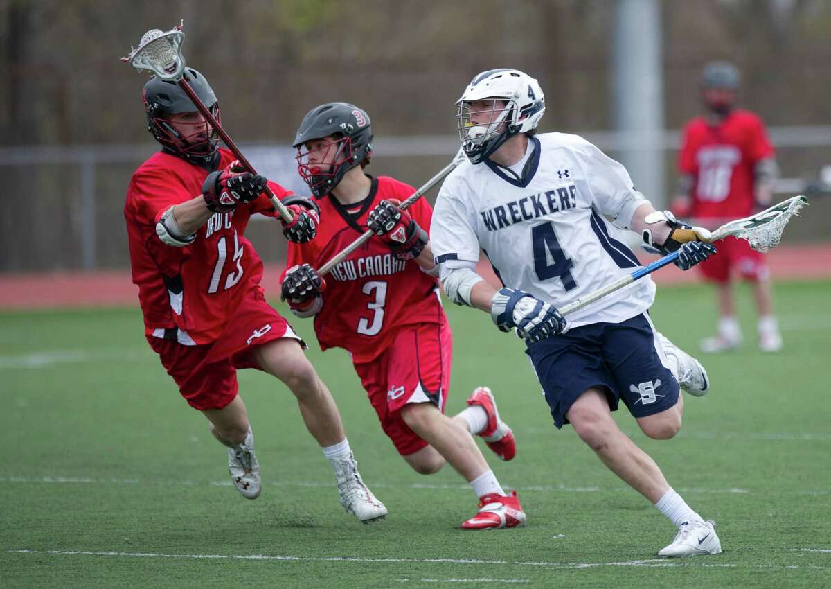 Staples' Colin Bannon carries the ball as he is defended by New Canaan's Thomas Costigan, left, and Jack Gilio, center, during Saturday's lacrosse game in Westport, Conn., on April 20, 2013.