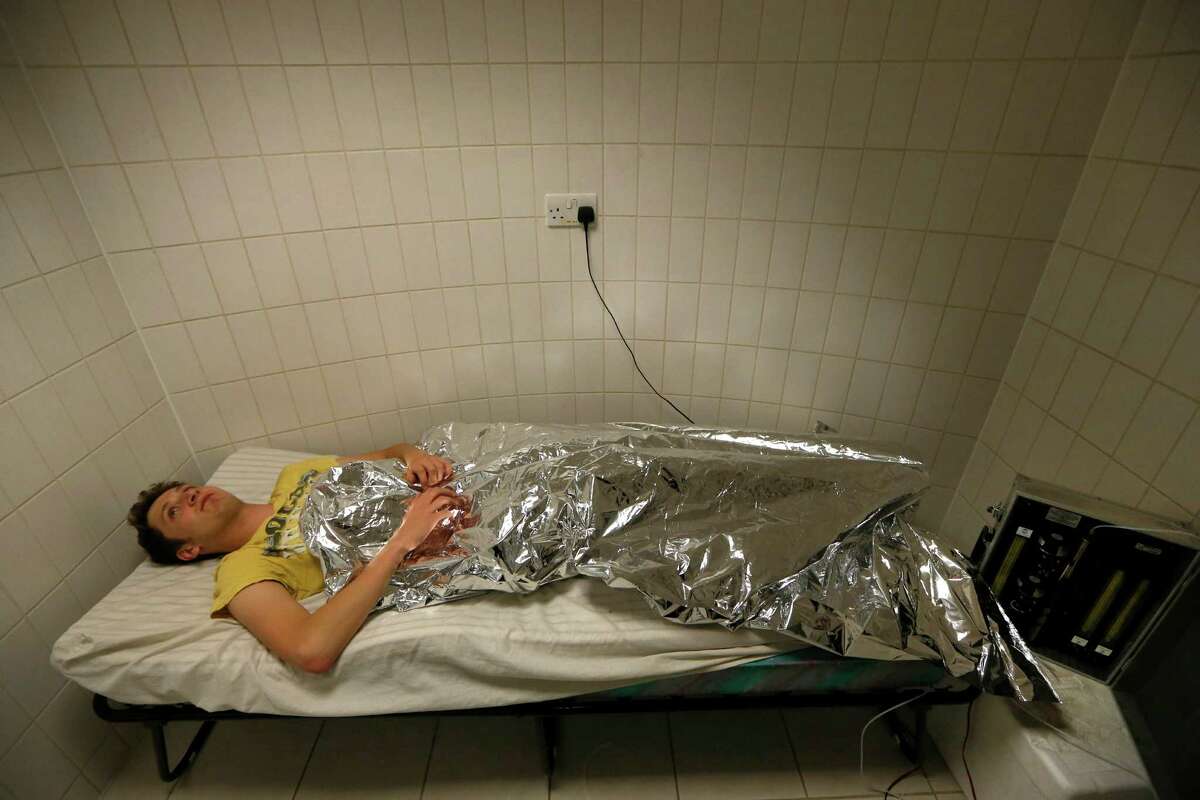 Volunteer Felix Preston lies in a odor extractor in a mosquito laboratory at the London School of Hygiene and Tropical Medicine in London, Thursday, May 30, 2013. Researchers at the school have discovered that malaria-infected mosquitoes are more attracted to human odours. (AP Photo/Sang Tan)