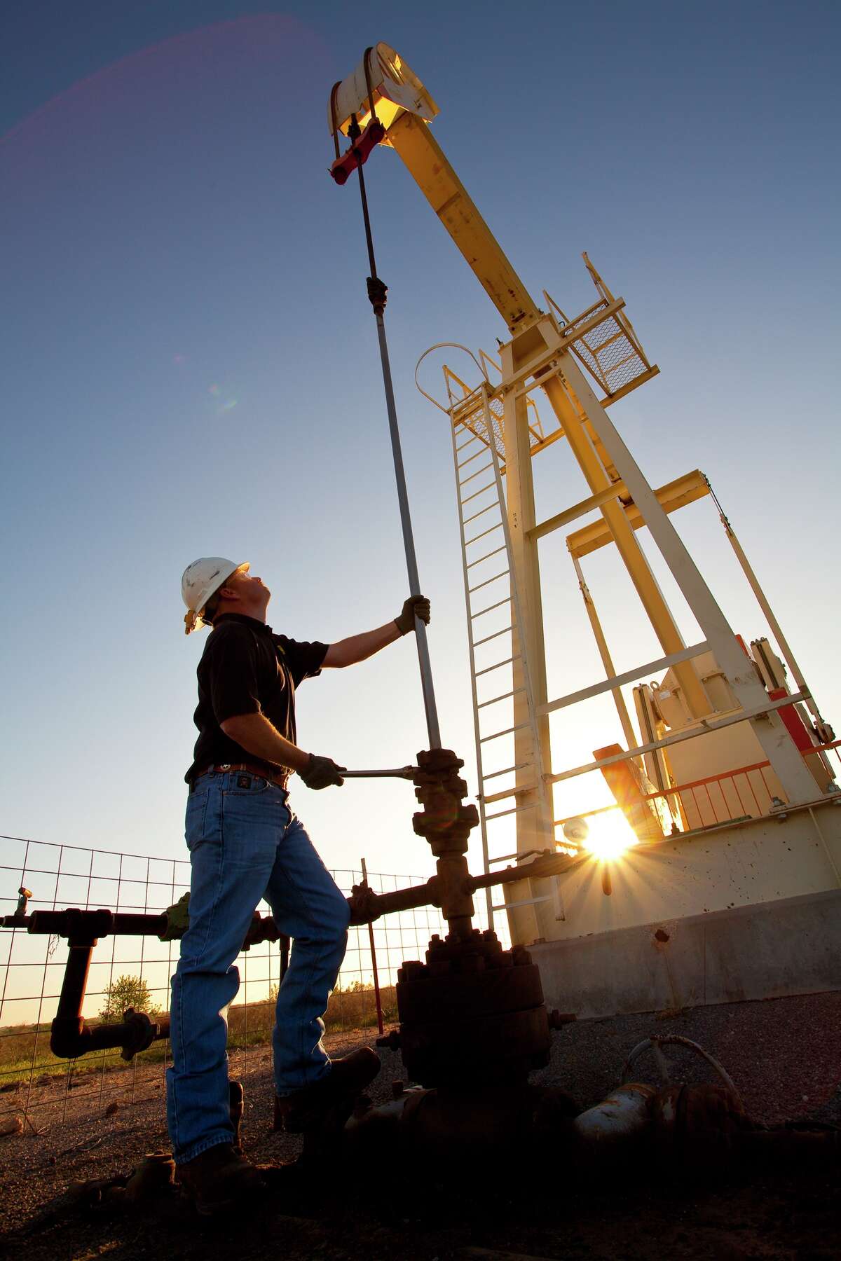 A pumpjack looms over a worker at a Linn Energy site in the Permian Basin of West Texas.