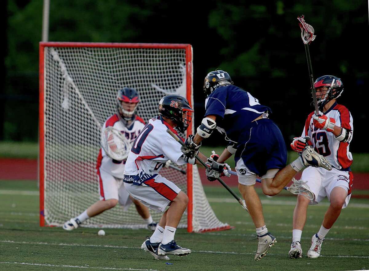 Mike Ross Connecticut Post freelance -Wilton High School's # 4 Henry Lee shoots and scores on goal as New Fairfield defender's # 20 Jason Mellilo and #13 John Gephart defend during second period action at Wednesday evening Class M semifinals. Wilton would win 10-3.
