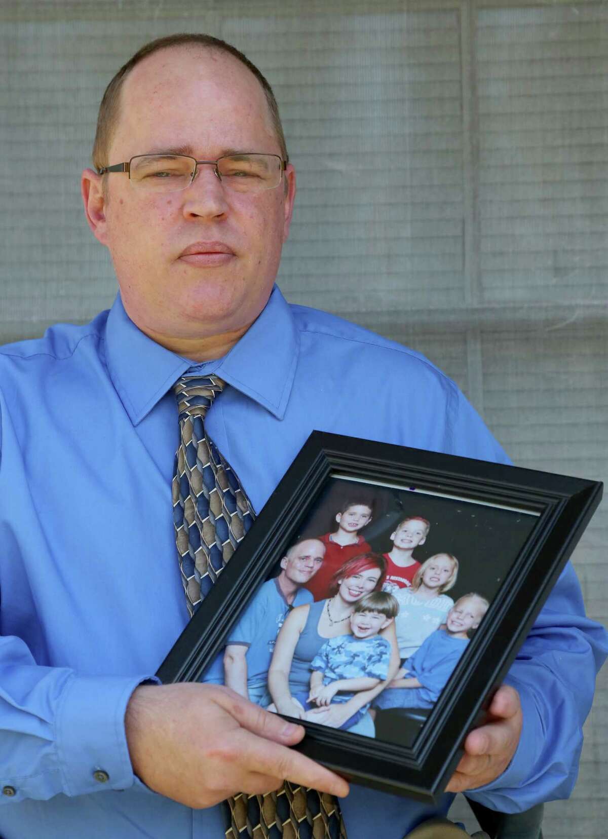 David Brasse holds a family portrait on his porch of his home in Alvin. He and then-fiancee Samantha Britain had been investigated by CPS for two years before Sarah died in 2009.