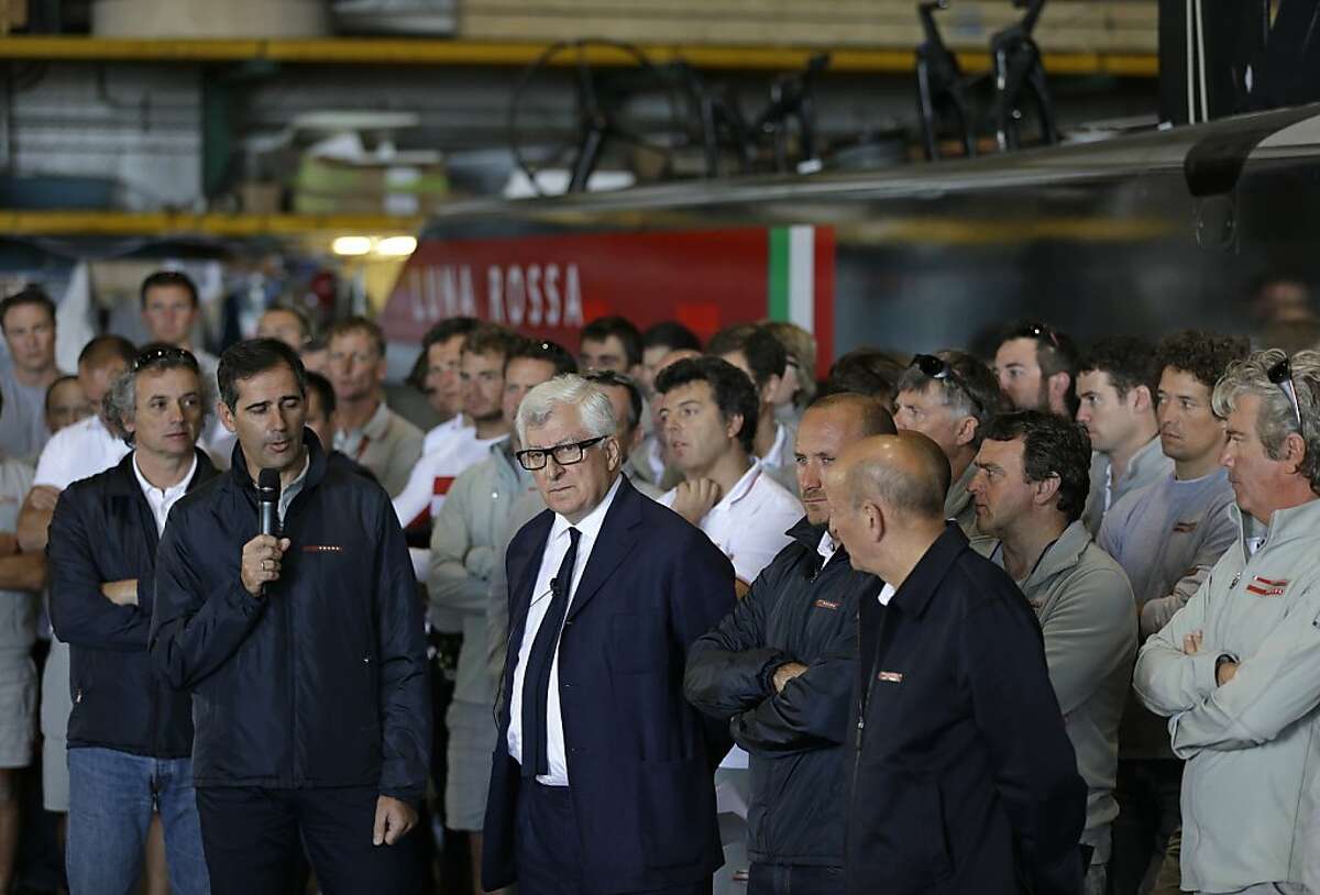Luna Rossa Challenge owner Patrizio Bertelli, center, listens to questions while standing with team members during a news conference at the America's Cup team's base Friday, May 17, 2013 in Alameda Calif. The owner of the Italian entry in the America's Cup says his boat will compete this summer, but sought new safety measures after the death of a sailor on a training run last week. Bertelli announced at a press conference at his team's Alameda headquarters that he wanted races canceled if winds on the San Francisco Bay were deemed too dangerous. (AP Photo/Eric Risberg)