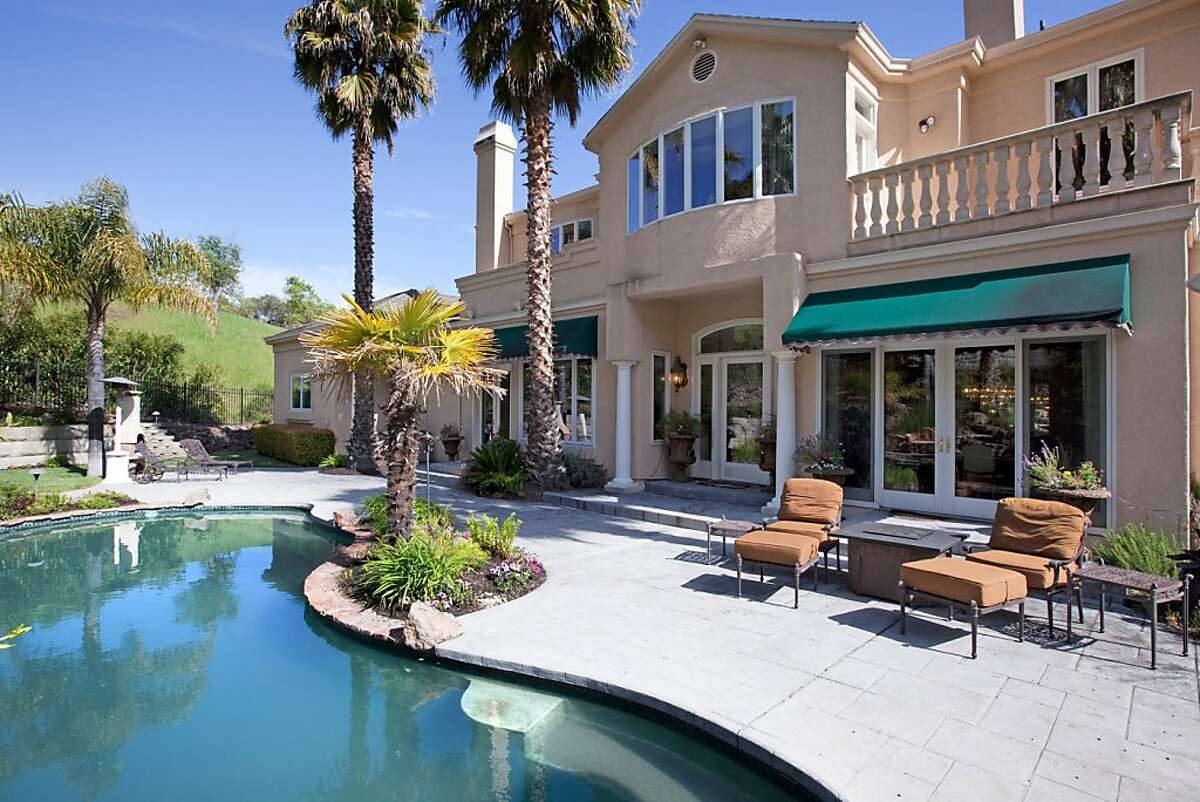 French doors off the dining room open to a patio and backyard that includes a pool and built-in barbecue.