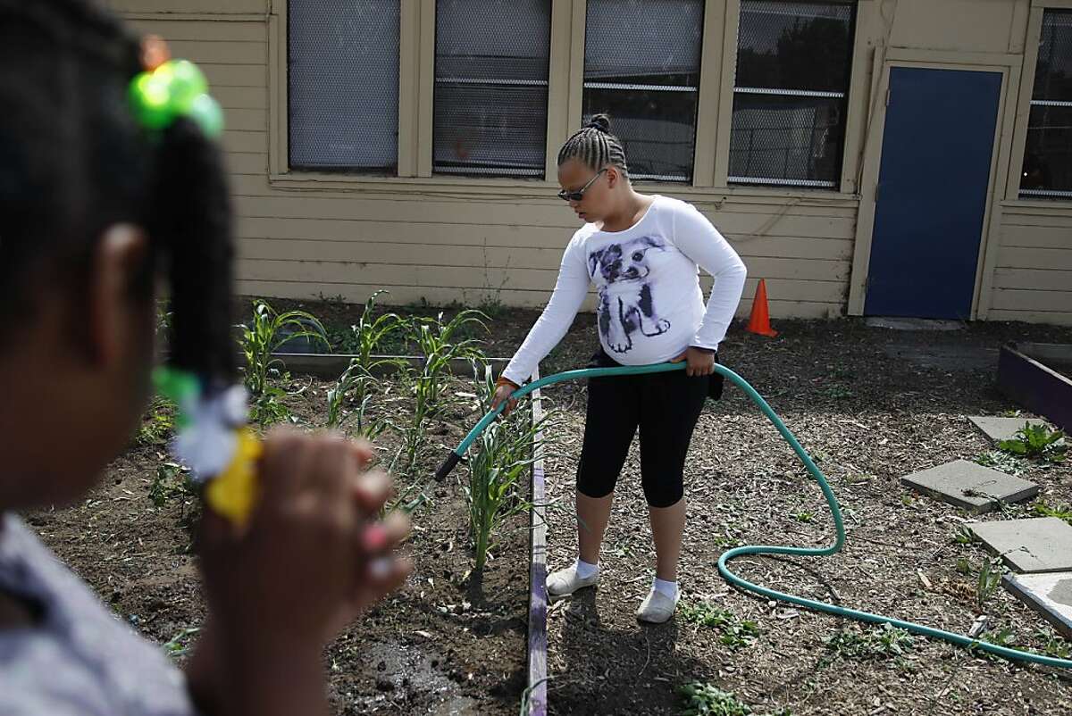 Samia Shorts (right), 10, of Vallejo waters plants in the garden at the Continentals of Omega Boys and Girls Club as Diamond Crosley (left), 8, of Vallejo watches on Monday, June 10, 2013 in Vallejo, Calif. The Community Gardens and Nutrition Education project was one of the projects that Vallejo residents voted on through the participatory budgeting vote.