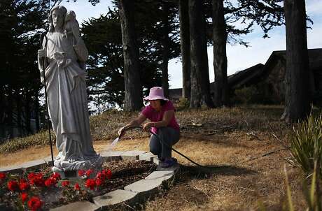 Sister Anna Tram Nguyen waters flowers in front of the Convent of the Good Shepherd on University Mound.