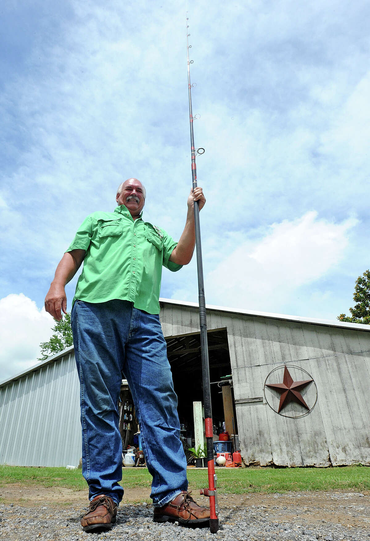 Lou McEachern stands Monday with the 13 foot eight inch fishing pole that he used to make a 700 foot cast over the Astrodome in January of 1991. Photo taken Monday, June 10, 2013 Guiseppe Barranco/The Enterprise