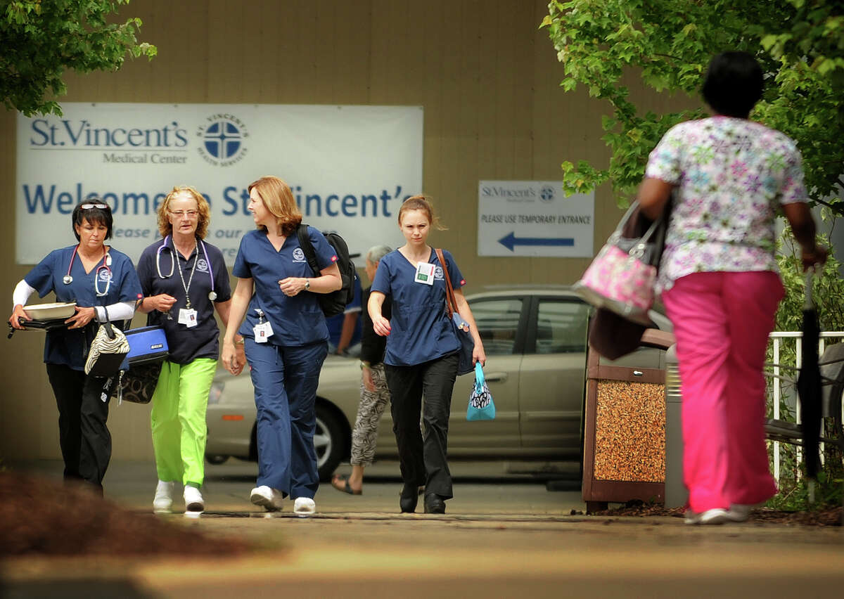 Employees cross paths during a shift change outside St. Vincent's Medical Center in Bridgeport, Conn. on Tuesday, June 11, 2013. The hospital announced layoffs of up to forty eight employees.