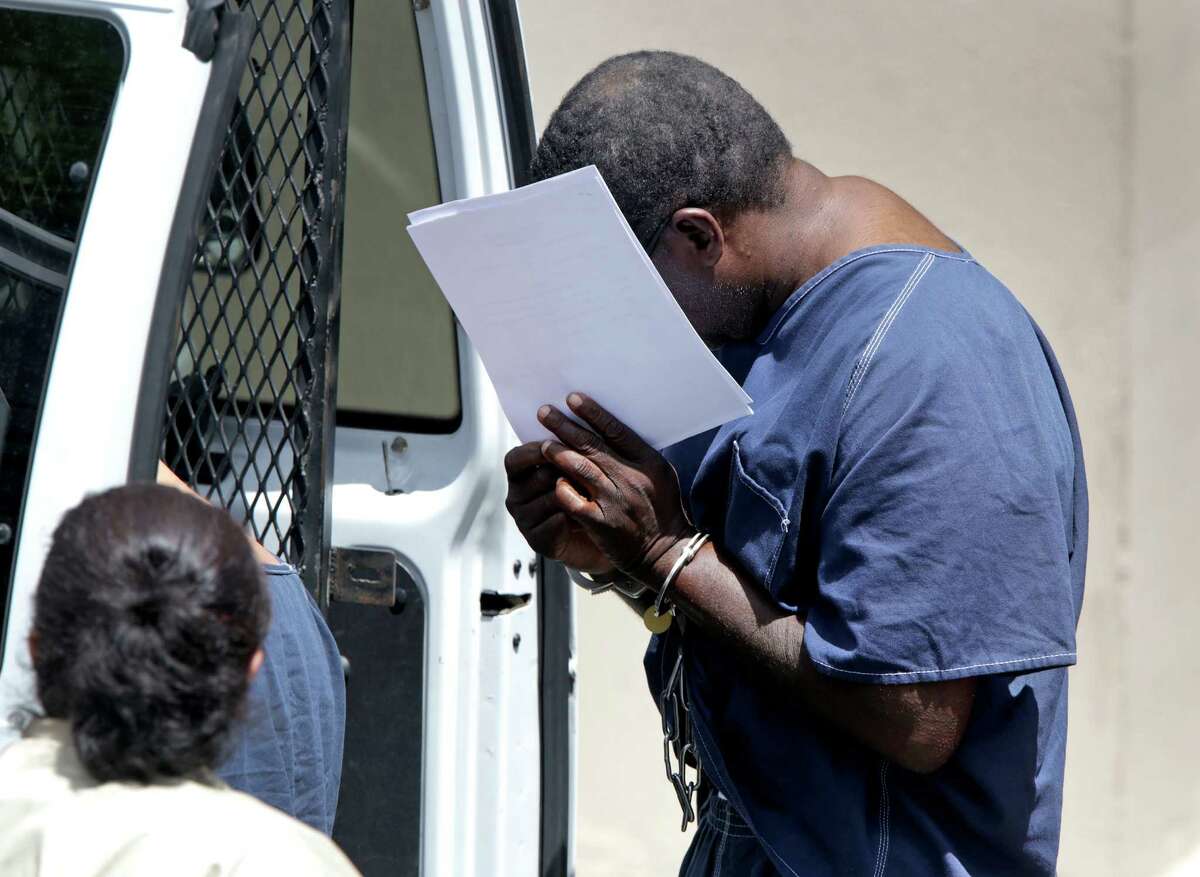 Alvin Leon Roundtree, covering his face with papers, leaves the Federal Courthouse in chains where he was charged with domestic violence on a military base, on Tuesday, June 11, 2013.