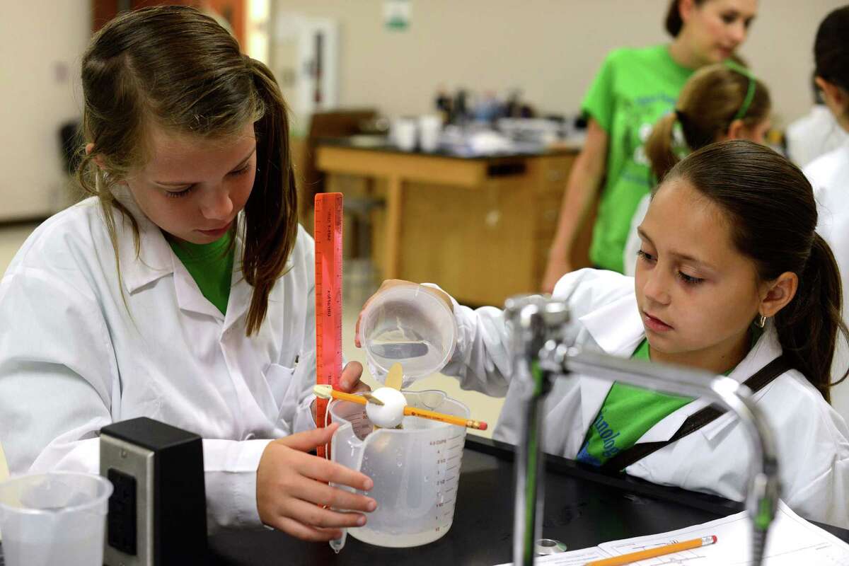 Kaycee Mabe (left) and Lauryn Brynelsen conduct a water power experiment using a handmade water wheel at the Karnes County Eagle Ford Energy Camp.