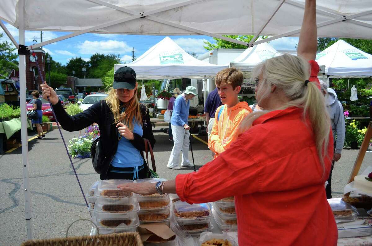 Lolly Turner, at right in red, talks with all the customers that approach her tent at the Darien Farmer's Market -- often asking if they would like to sample one of the various pies she has for sale.