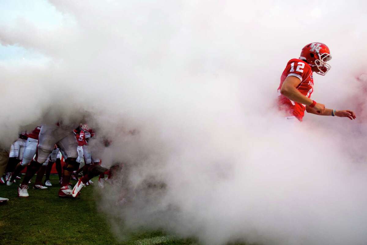 Houston quarterback Rex Dausin (12) runs through a cloud of smoke as he runs out with the team before the start of an NCAA football game against Louisiana Tech at Robertson Stadium, Saturday, Sept. 8, 2012, in Houston. ( Brett Coomer / Houston Chronicle )