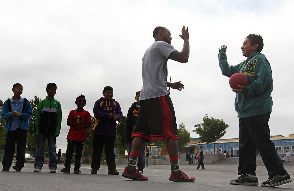 Peter Best a programs coordinator for PlayWorks gets a high five from Sebastian Alvaradon at Montalvin Elementary School during recess Wednesday, June 5, 2013 in San Pablo Calif. At a time when recess and other play time is under pressure to make more time for test preparation and basic academics, a nonprofit is working hard to explain how schools can make recess count. PlayWorks works in a number of Bay Area schools to coach kids to improve the school-learning environment by explaining why play matters. The results are a decrease in bullying and aggressive actions and an uptick in academic performance.