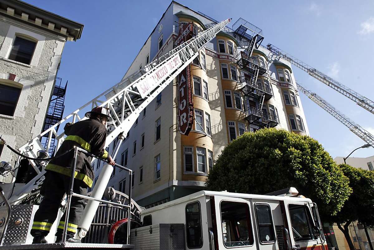 Firefighters mop up as residents of the Senator Hotel stood out on the street after a fire broke out on the roof of the building on Tuesday, June 18, 2013, in San Francisco, Calif.