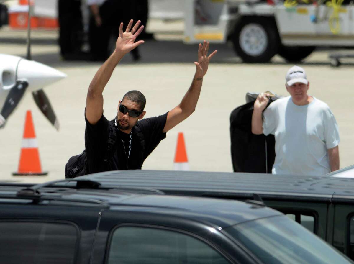 Tim Duncan waves before getting into his car after the San Antonio Spurs team members arrived at San Antonio International Airport on Friday, June 21, 2013, after representing the NBA's Western Conference in the Championship Series. They lost to the Miami Heat. Head coach Gregg Popovich is at right.