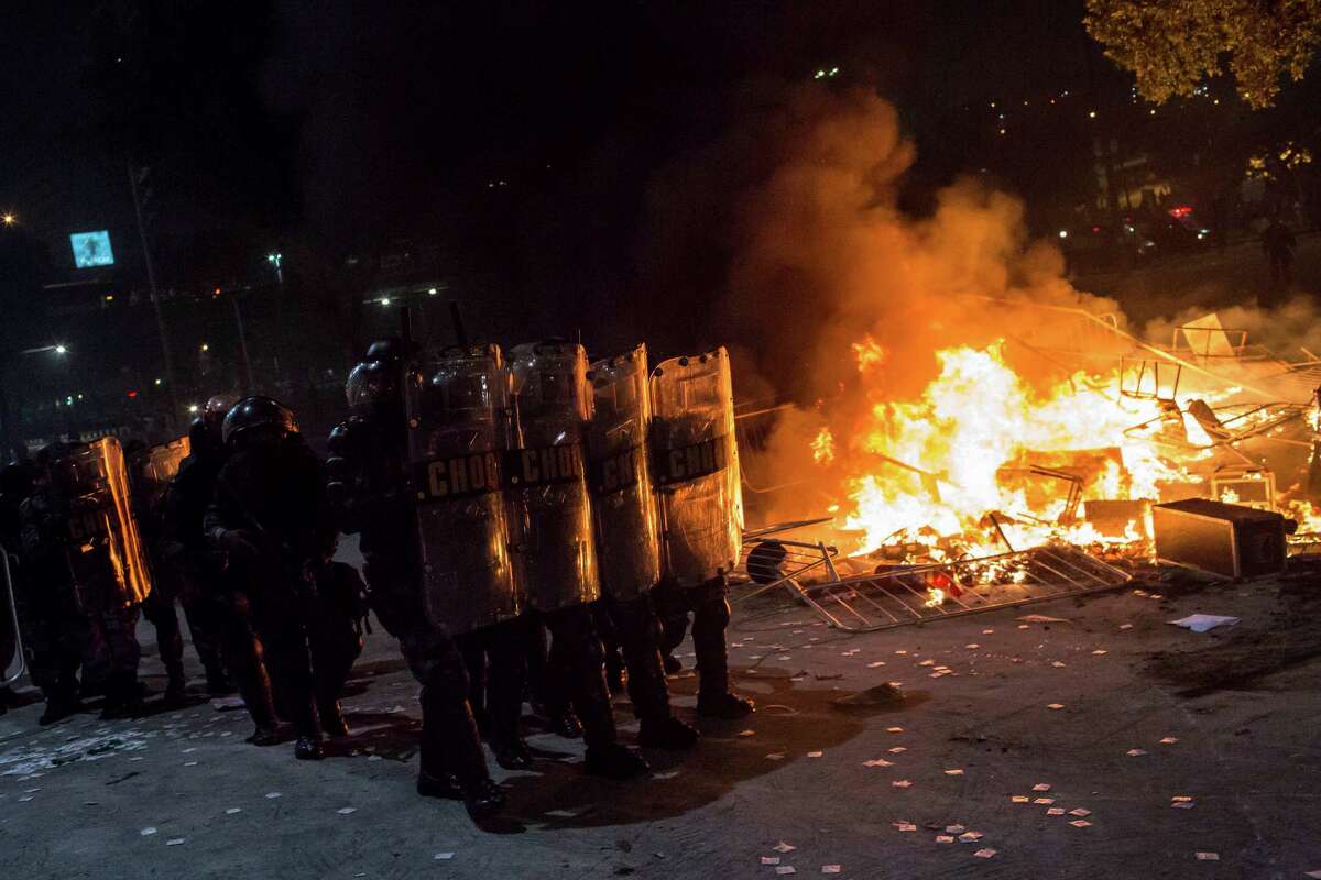 Riot police move towards protesters next to burning barricades during a protest in Rio de Janeiro, Brazil, Thursday, June 20, 2013. More than half a million Brazilians poured into the streets of at least 80 Brazilian cities Thursday in demonstrations that saw violent clashes and renewed calls for an end to government corruption and demands for better public services. Riot police battled protesters in at least five cities, with some of the most intense clashes happening in Rio de Janeiro, where an estimated 300,000 demonstrators swarmed into the seaside city's central area. (AP Photo/Felipe Dana)