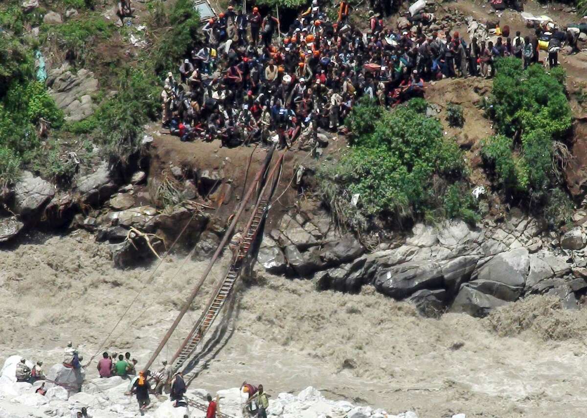 Indo-Tibetan Border Police (ITBP) personnel, in uniform, help stranded pilgrims on a makeshift bridge cross a stream of gushing floodwater at Govind Ghati, in Chamoli district, in northern Indian state of Uttarakhand, India, Friday, June 21, 2013. A top official in a northern Indian state hit by heavy monsoon rains said more than 500 people died in the flooding and landslides. The heavy rains caused by the annual monsoon have also stranded tens of thousands, mostly pilgrims, in the mountainous region. (AP Photo)