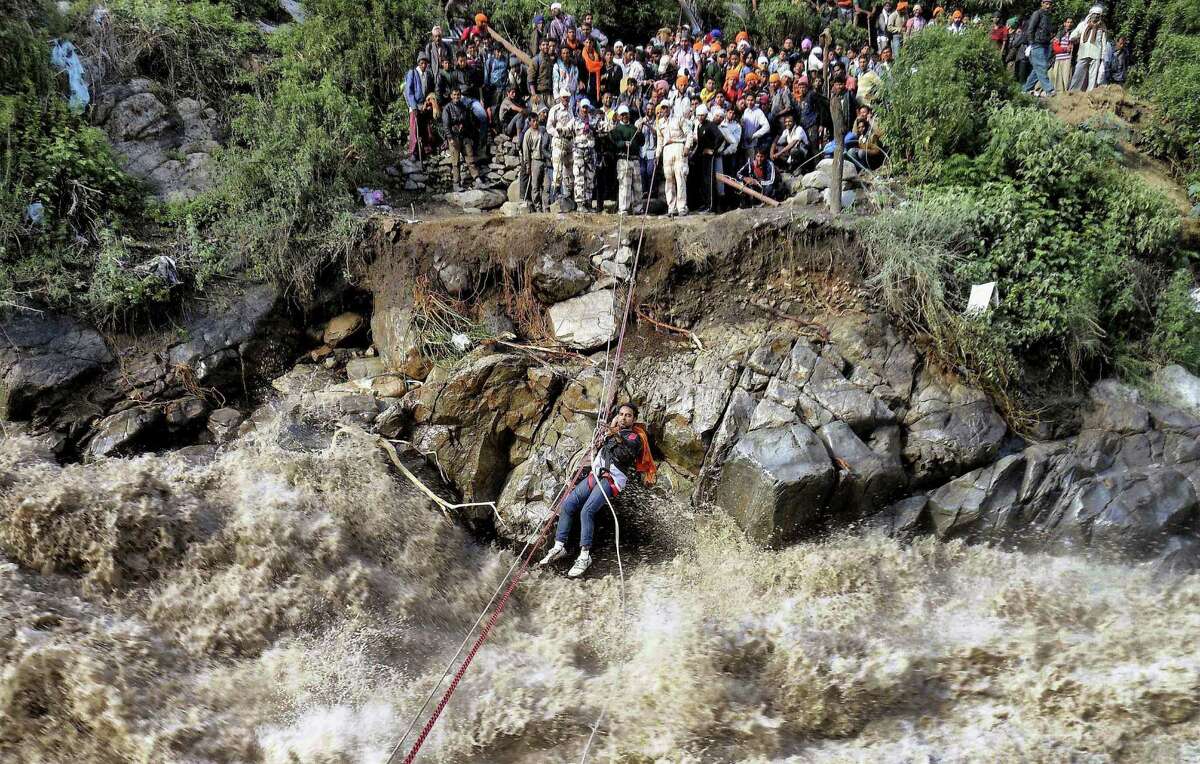 In this Thursday, June 20, 2013 photo, Indo-Tibetan Border Police (ITBP) use a rope to rescue stranded pilgrims cross a river swollen by flood waters at Govind Ghat, in Chamoli district, in northern Indian state of Uttarakhand, India. Uttrakhand spokesman Amit Chandola said the rescue operation centered on evacuating nearly 27,000 people trapped in the worst-hit Kedarnath temple area â?” one of the holiest Hindu temples dedicated to Lord Shiva, located atop the Garhwal Himalayan range. (AP Photo)