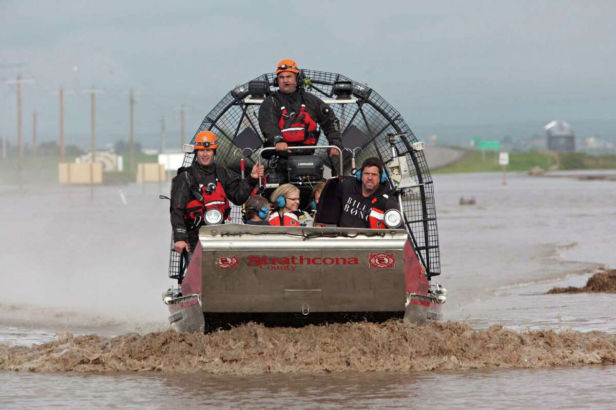 A search and rescue boat carries rescued passengers from a flooded industrial site near highway 543 north of High River, Alberta, Canada on Friday, June 21, 2013. The rescued passengers spent the night moored on a structure they built in the water. Calgary's mayor said Friday the flooding situation in his city is as under control as it can be, for now. Officials estimated 75,000 people have been displaced in the western Canadian city. Mayor Naheed Nenshi said the Elbow River, one of two rivers that flow through the southern Alberta city, has peaked. (AP Photo/The Canadian Press, Jordan Verlage)
