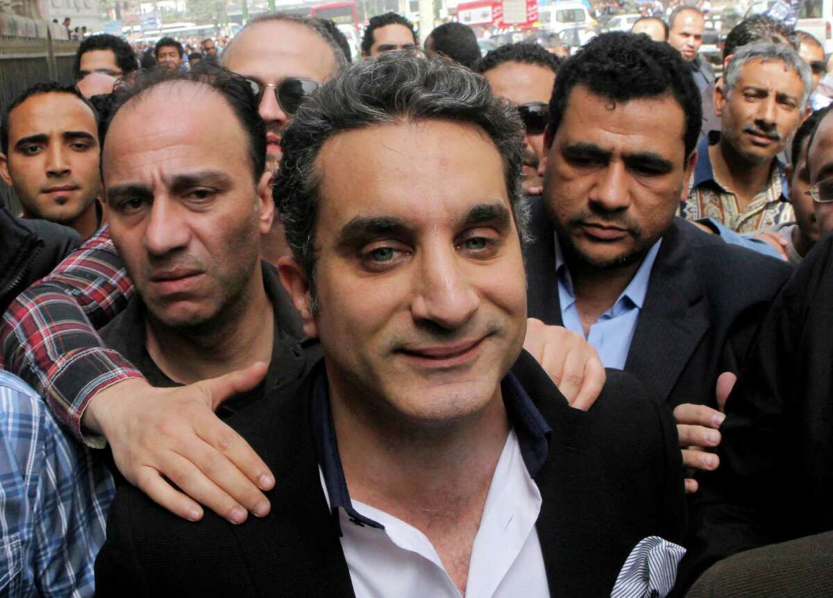 FILE - In this Sunday, March 31, 2013 file photo, a bodyguard secures popular Egyptian television satirist Bassem Youssef, who has come to be known as Egypt's Jon Stewart, as he enters Egypt's state prosecutors office to face accusations of insulting Islam and the country's Islamist leader in Cairo, Egypt. U.S. satirist Jon Stewart appears Friday, June 21, 2013 on a talk show with Bassem Youssef, known as Egypt's Jon Stewart(AP Photo/Amr Nabil, File)