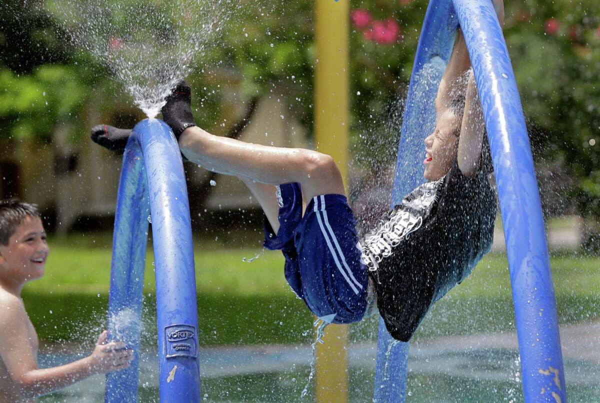 Jonathan Flores, 10, left, and Eduardo Vargas, 11, right, play at Hidalgo Park sprayground on Friday, June 21, 2013.