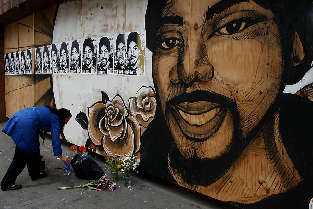 Oakland resident Julia Hutton lays flowers on the sidewalk in front of the Oscar Grant mural on 17th and Broadway on Friday following violent demonstrations over the Johannes Mehserle conviction on Thursday.