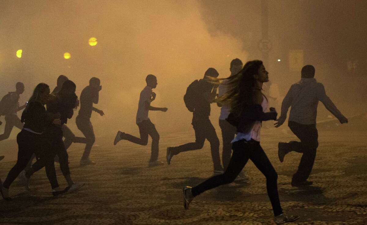 Protesters run from clouds of tear gas in Rio de Janeiro on Thursday. Clashes went into the early hours of Friday.