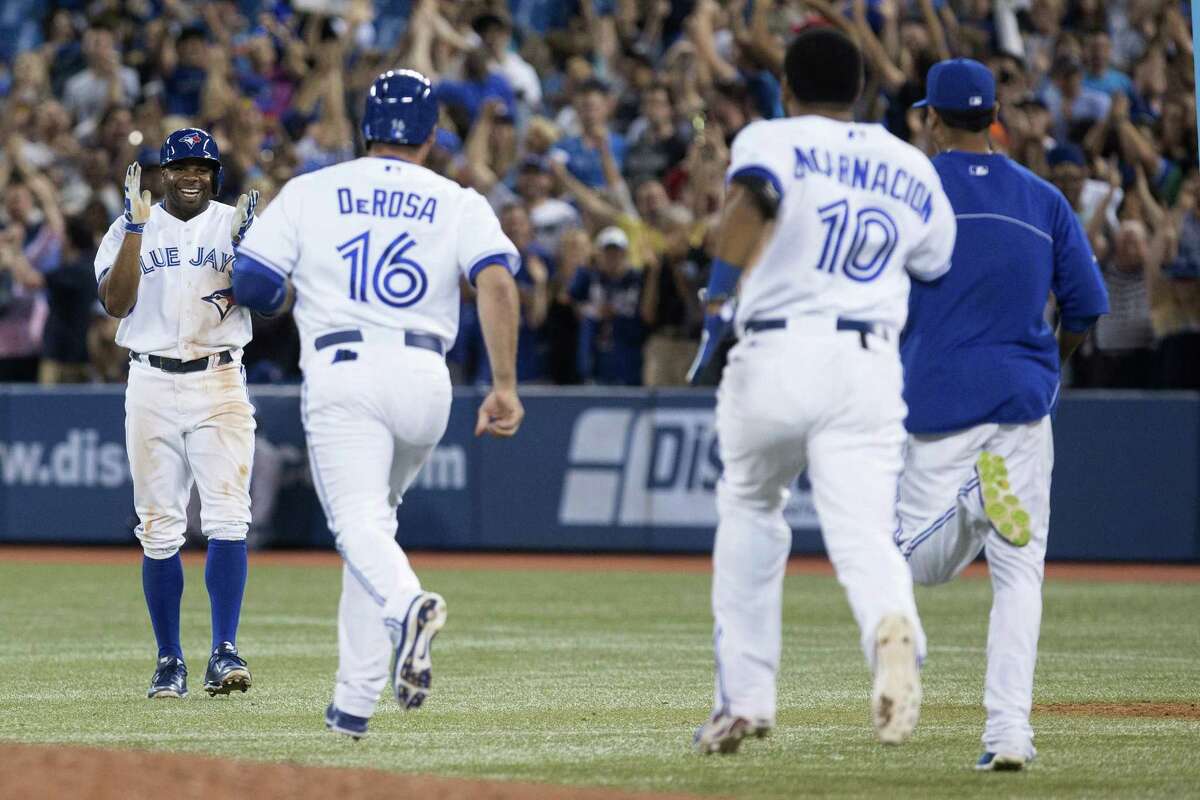 The Blue Jays' Rajai Davis (left) celebrates with his teammates after driving home the winning run.